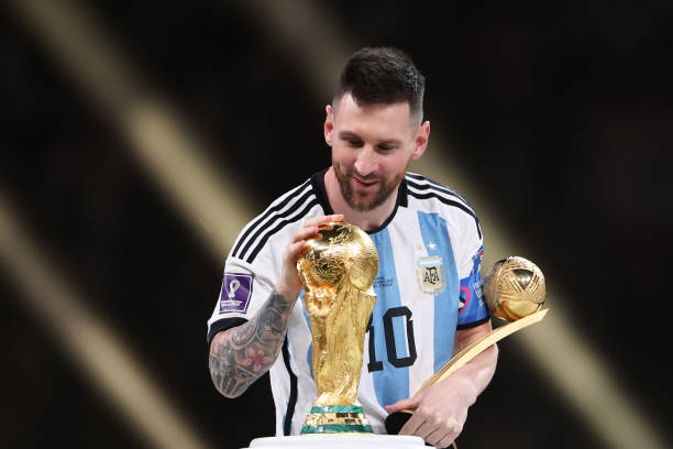 Messi holding the fifa world cup trophy and the golden ball award after Argentina defeated France on penalty kicks